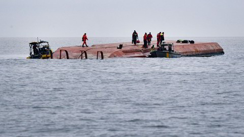 Divers work on the capsized Danish cargo ship Karin Hoej, right, after it collided with British cargo vessel Scot Carrier in the Baltic Sea, between Ystad and Bornholm, Sweden, Monday, Dec. 13, 2021. Two cargo ships collided in the Baltic Sea off southern Sweden and at least two people were reported missing Monday. One of the vessels capsized and will be towed to a Swedish port, authorities said. The maritime administration said it received a pre-dawn alarm that two cargo ships had collided south of Ystad in Sweden, close to the Danish island of Bornholm. The authority identified the ships as the Danish-flagged Karin Hoej and a British ship, the Scot Carrier. The Danish ship capsized fully and was floating upside down. (Johan Nilsson/TT via AP)